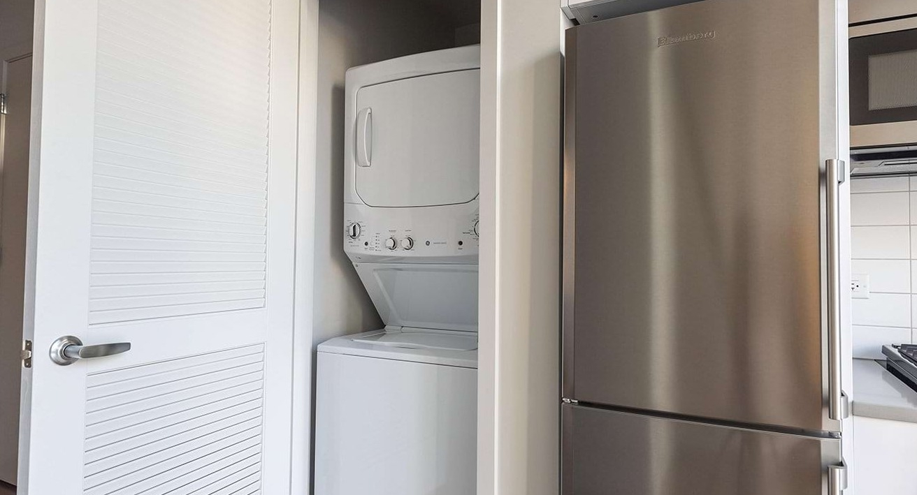 Convenient in-unit laundry closet at The Ardus in Chicago, featuring a stacked washer and dryer next to the kitchen