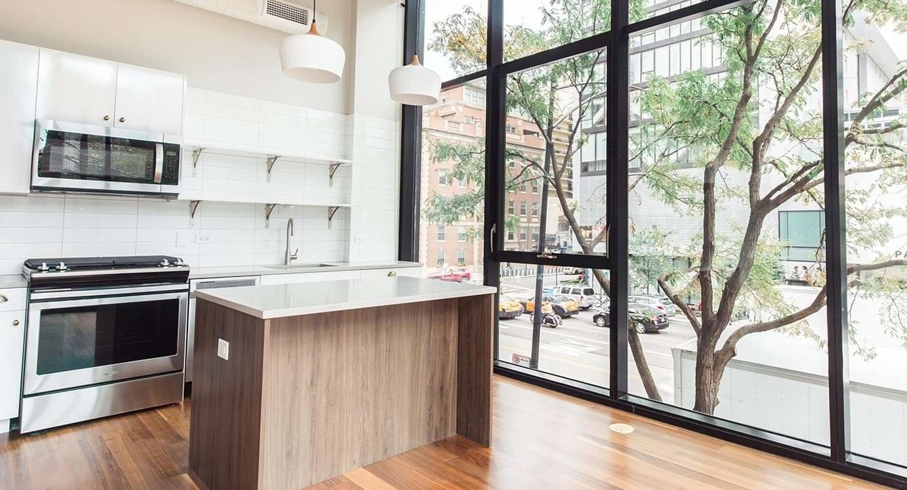 Bright apartment kitchen at The Ardus in Chicago, featuring a center island, white cabinets, and large windows overlooking the city