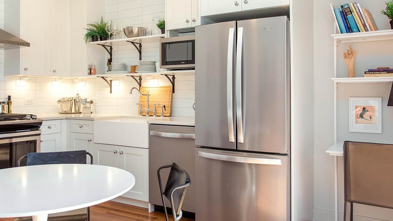 Modern apartment kitchen and dining area at The Ardus in Chicago, featuring white subway tiles, stainless steel appliances, and a round dining table