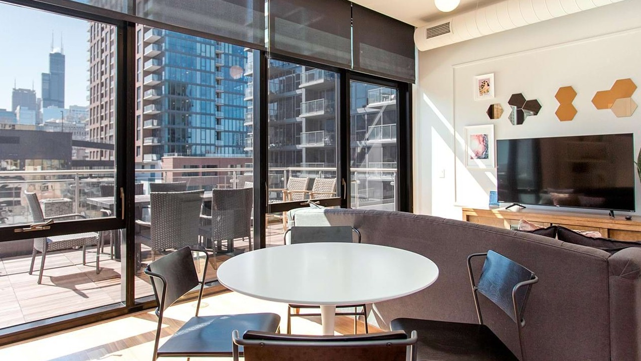 Bright open-concept living and dining area at The Ardus in Chicago, with access to a private balcony and city views.