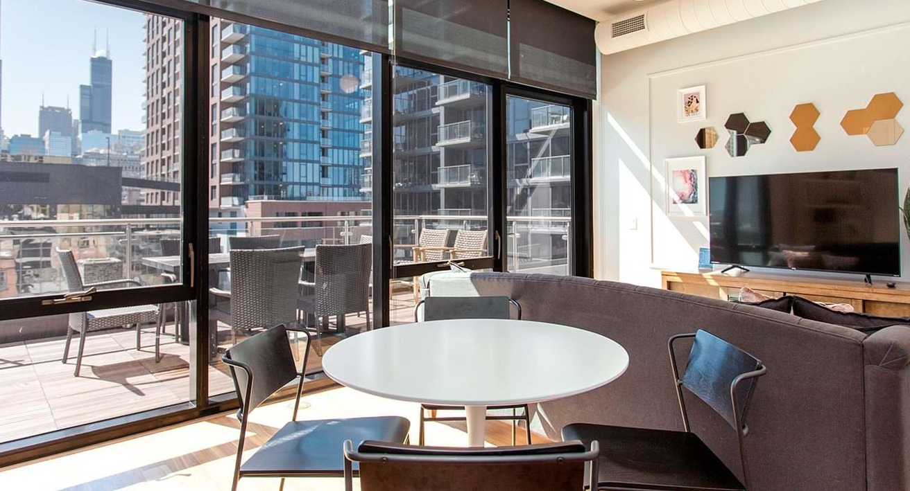 Bright open-concept living and dining area at The Ardus in Chicago, with access to a private balcony and city views.