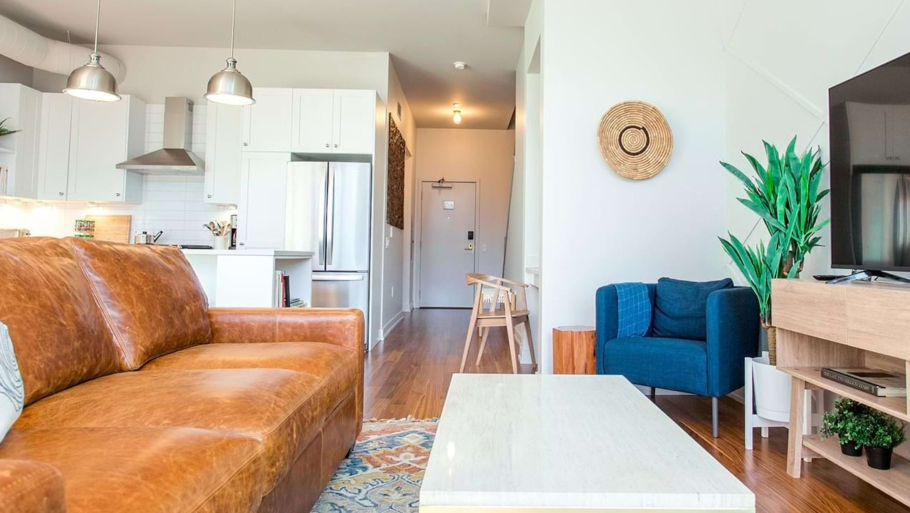 Spacious open-concept living area at The Ardus in Chicago, featuring a comfortable leather sofa, stylish rug, and exposed ductwork