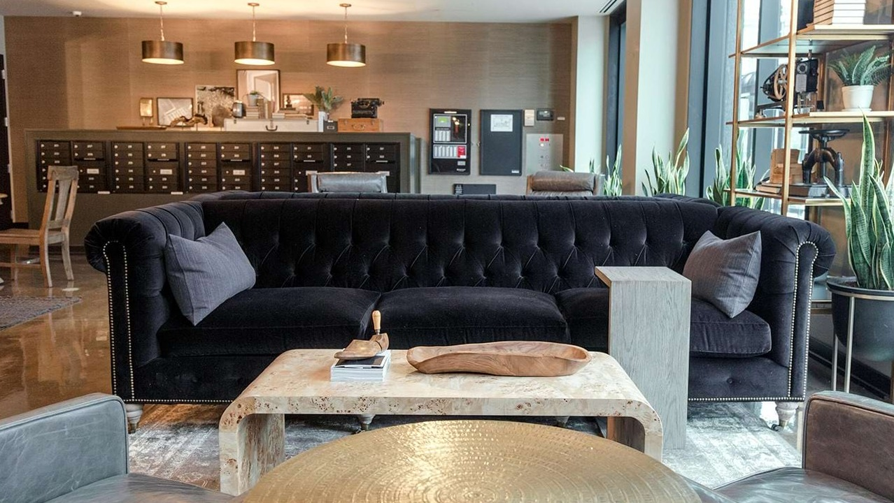 Elegant resident lounge at The Ardus in Chicago, featuring a plush black sofa, unique coffee tables, and a mailroom area