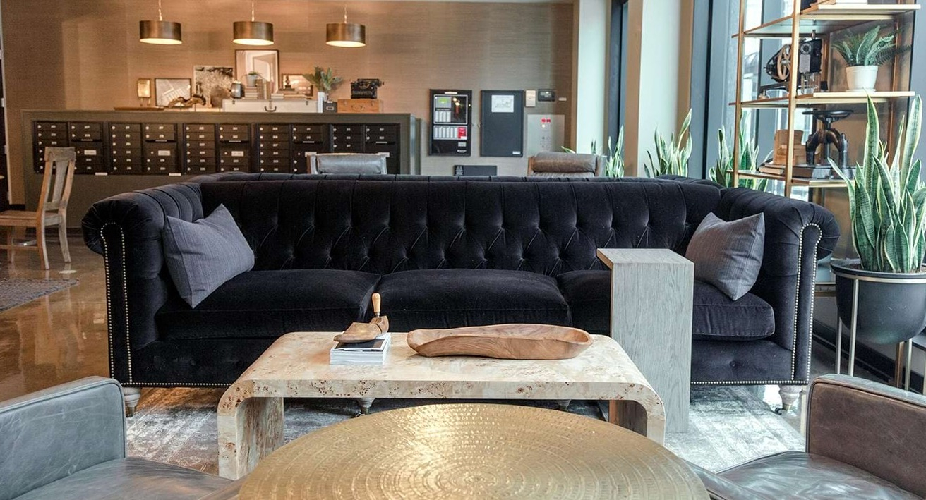 Elegant resident lounge at The Ardus in Chicago, featuring a plush black sofa, unique coffee tables, and a mailroom area