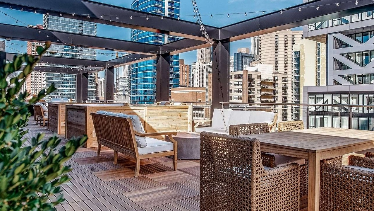 Inviting rooftop patio at The Ardus in Chicago, featuring comfortable dining and lounge areas with wooden decking and city views