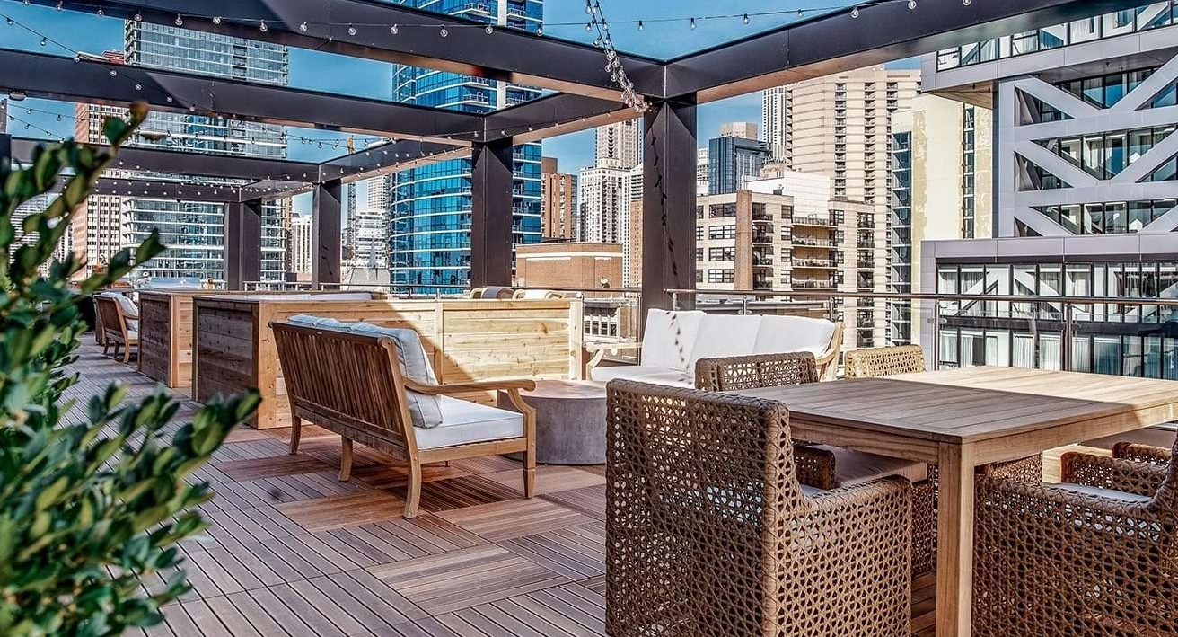 Inviting rooftop patio at The Ardus in Chicago, featuring comfortable dining and lounge areas with wooden decking and city views