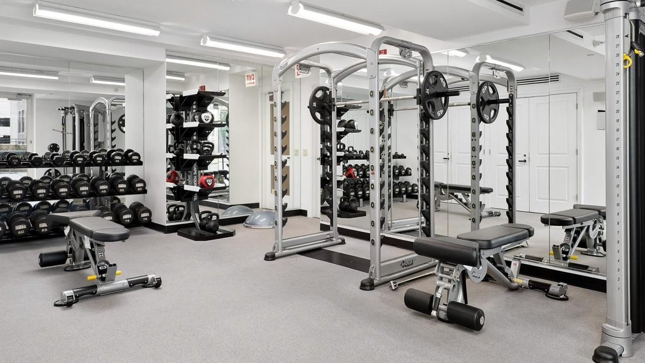 Spacious fitness center with a variety of weight machines, free weights, and ample space for strength training at The Bernardin Apartments in Chicago