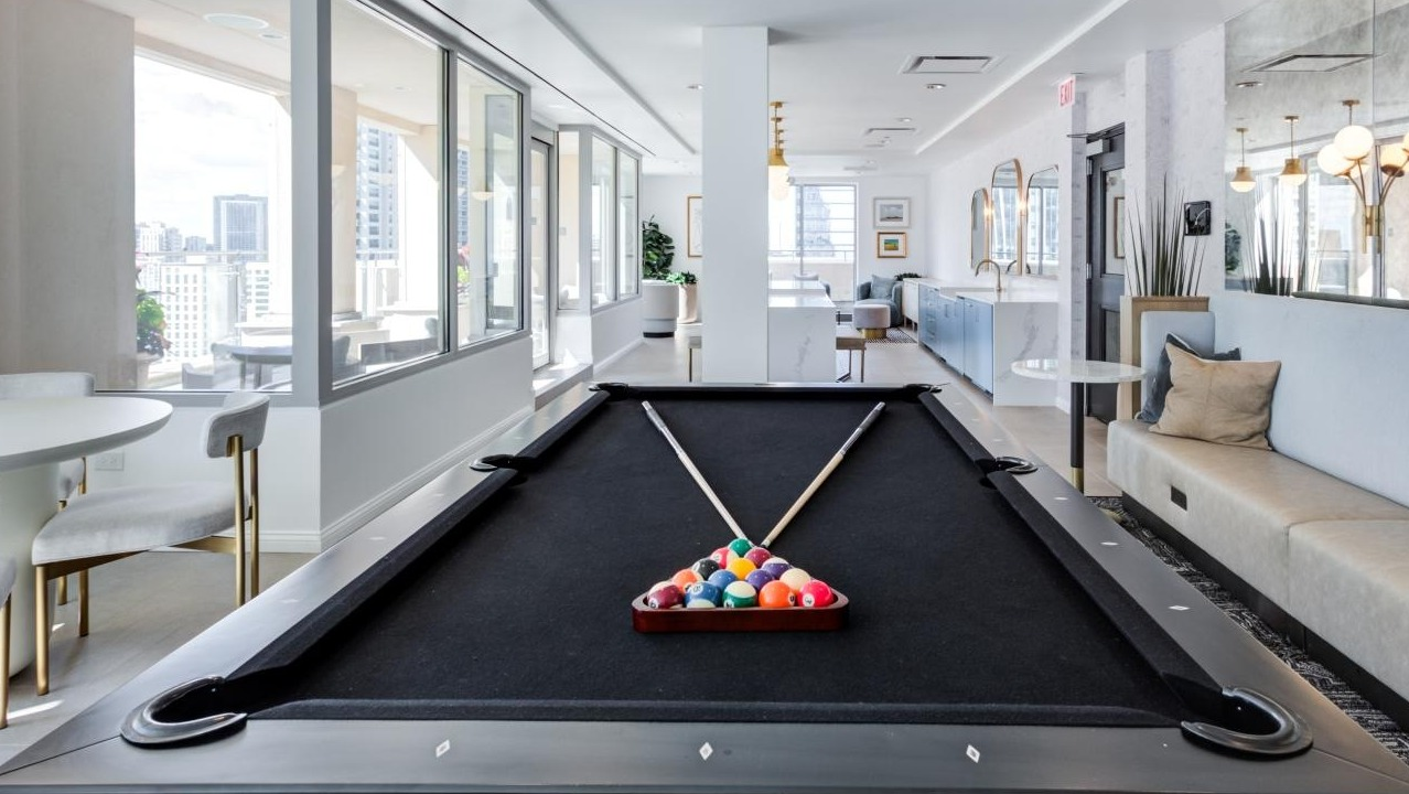 Bright and modern game room with a billiards table, comfortable seating, and large windows at The Bernardin Apartments in Chicago