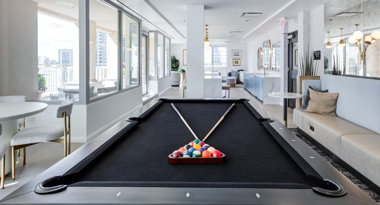 Bright and modern game room with a billiards table, comfortable seating, and large windows at The Bernardin Apartments in Chicago