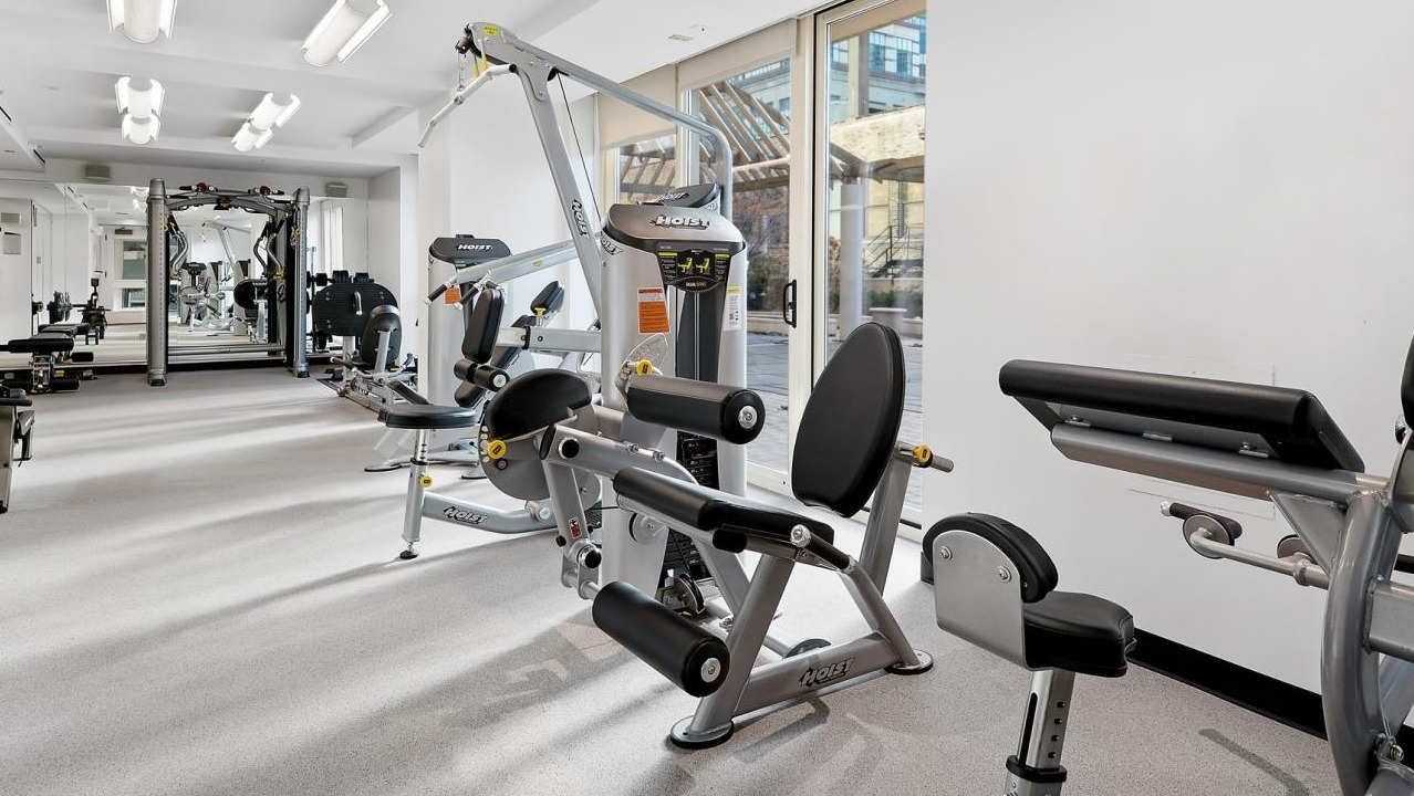 Well-equipped gym area featuring various modern strength training machines and natural light at The Bernardin Apartments in Chicago