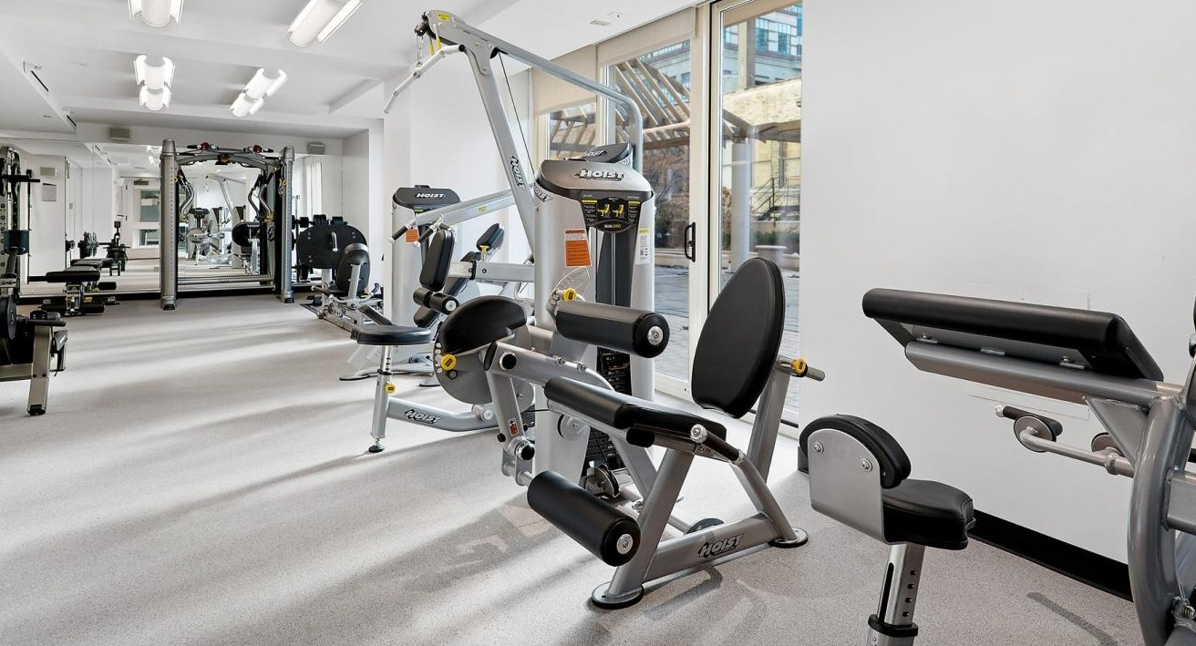 Well-equipped gym area featuring various modern strength training machines and natural light at The Bernardin Apartments in Chicago