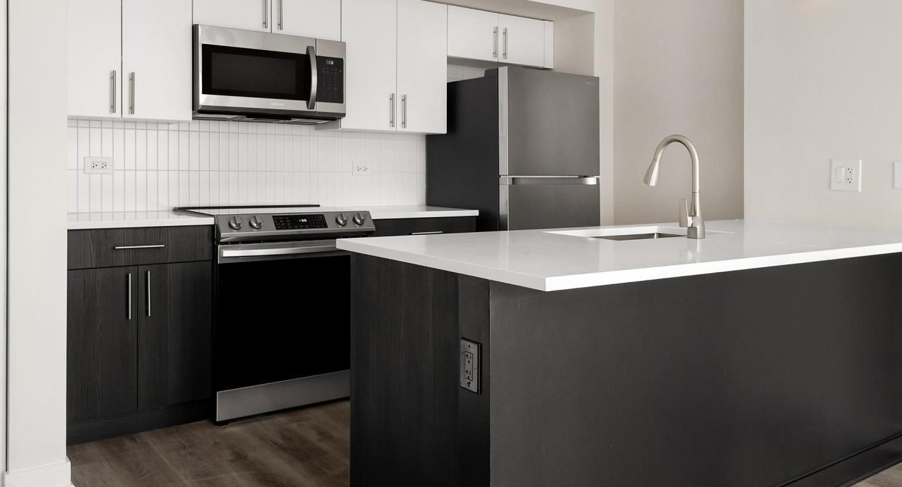 Sleek black and white kitchen with modern appliances, an island, and stylish pendant lighting at The Bernardin Apartments in Chicago