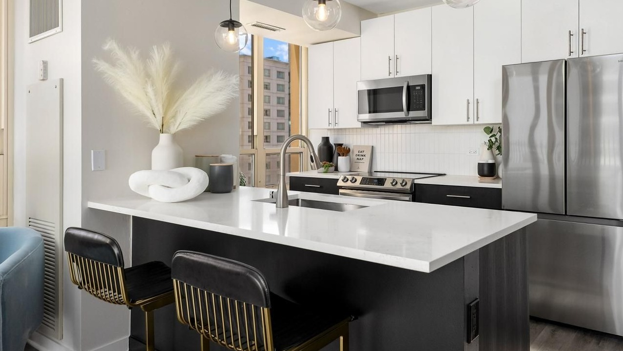Modern kitchen with a large island, elegant bar stools, stainless steel appliances, and stylish decor at The Bernardin Apartments in Chicago