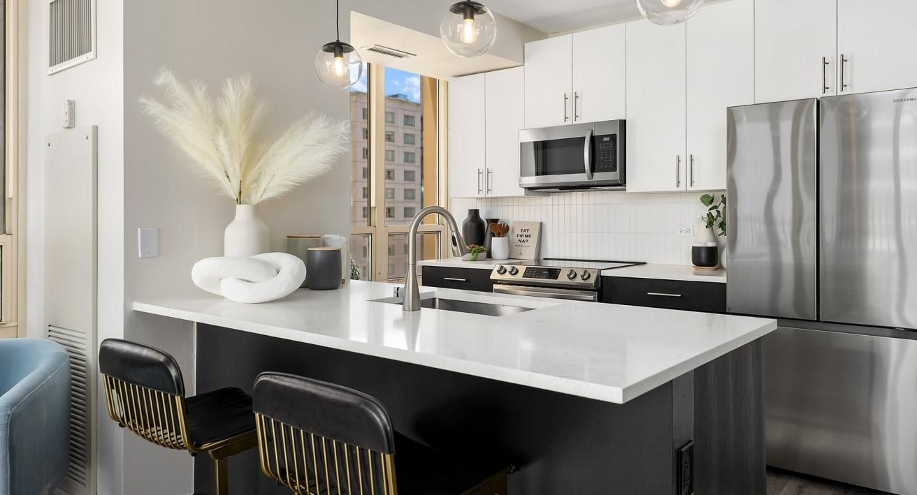 Modern kitchen with a large island, elegant bar stools, stainless steel appliances, and stylish decor at The Bernardin Apartments in Chicago
