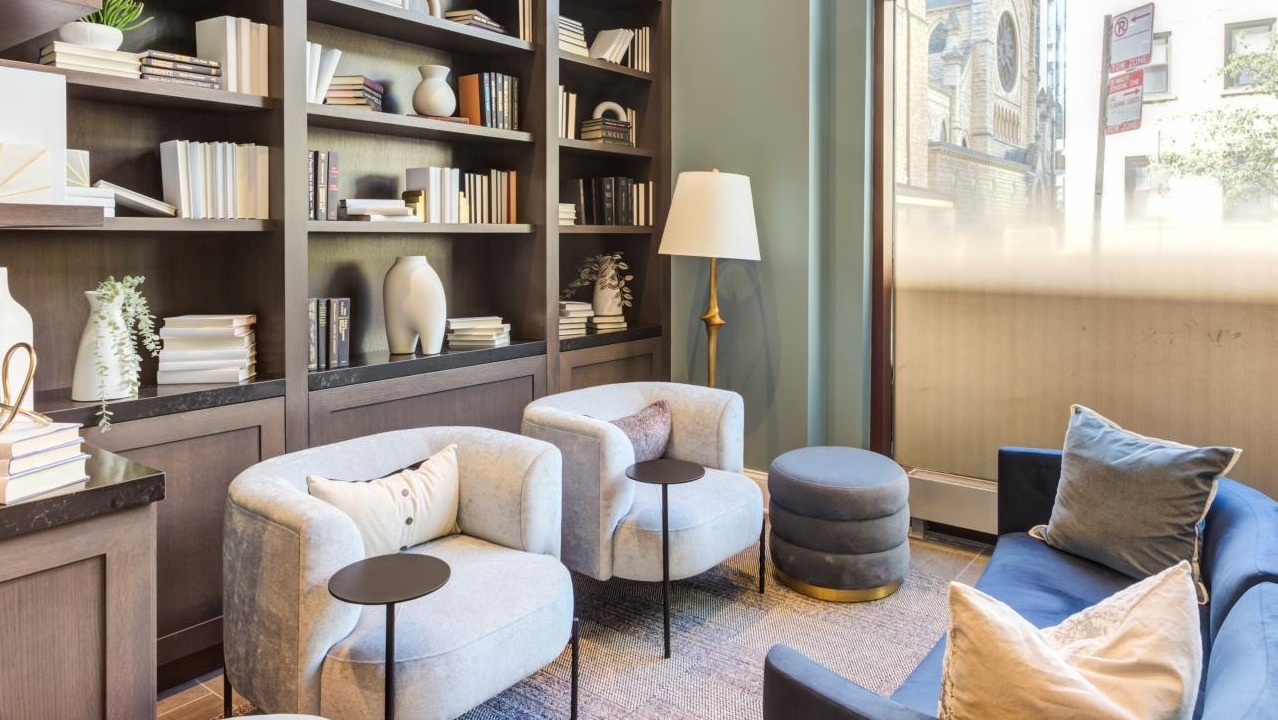 Cozy library lounge area with built-in bookshelves, comfortable armchairs, and soft lighting, ideal for reading at The Bernardin Apartments in Chicago
