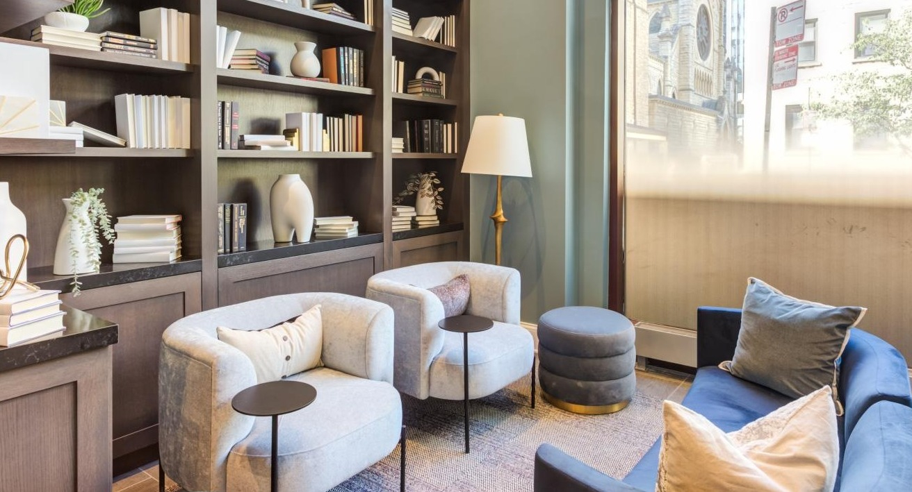 Cozy library lounge area with built-in bookshelves, comfortable armchairs, and soft lighting, ideal for reading at The Bernardin Apartments in Chicago