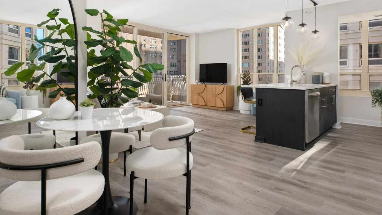 Spacious open-concept living room and kitchen with modern decor, a large plant, and an island at The Bernardin Apartments in Chicago