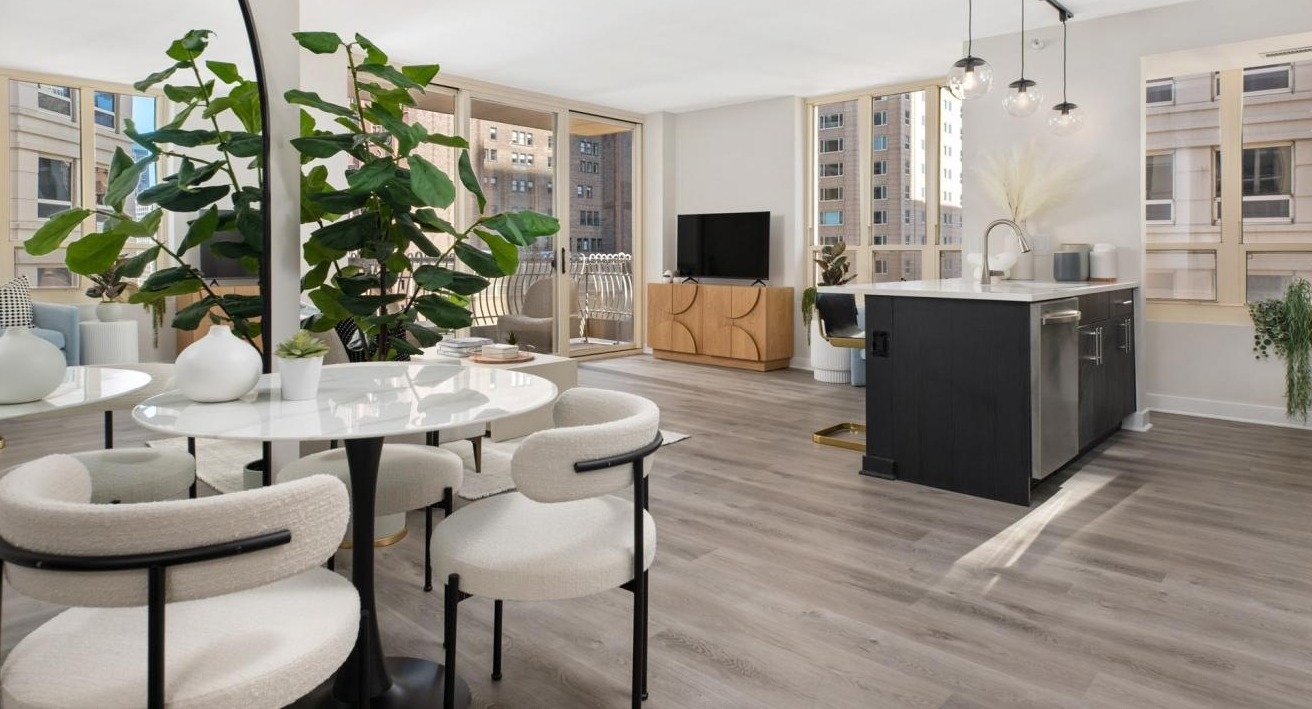 Spacious open-concept living room and kitchen with modern decor, a large plant, and an island at The Bernardin Apartments in Chicago