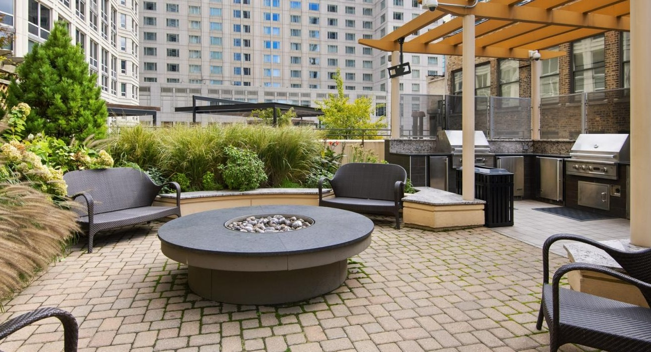 Lush outdoor patio area with grilling stations, a fire pit, and comfortable seating, ideal for entertaining at The Bernardin Apartments in Chicago