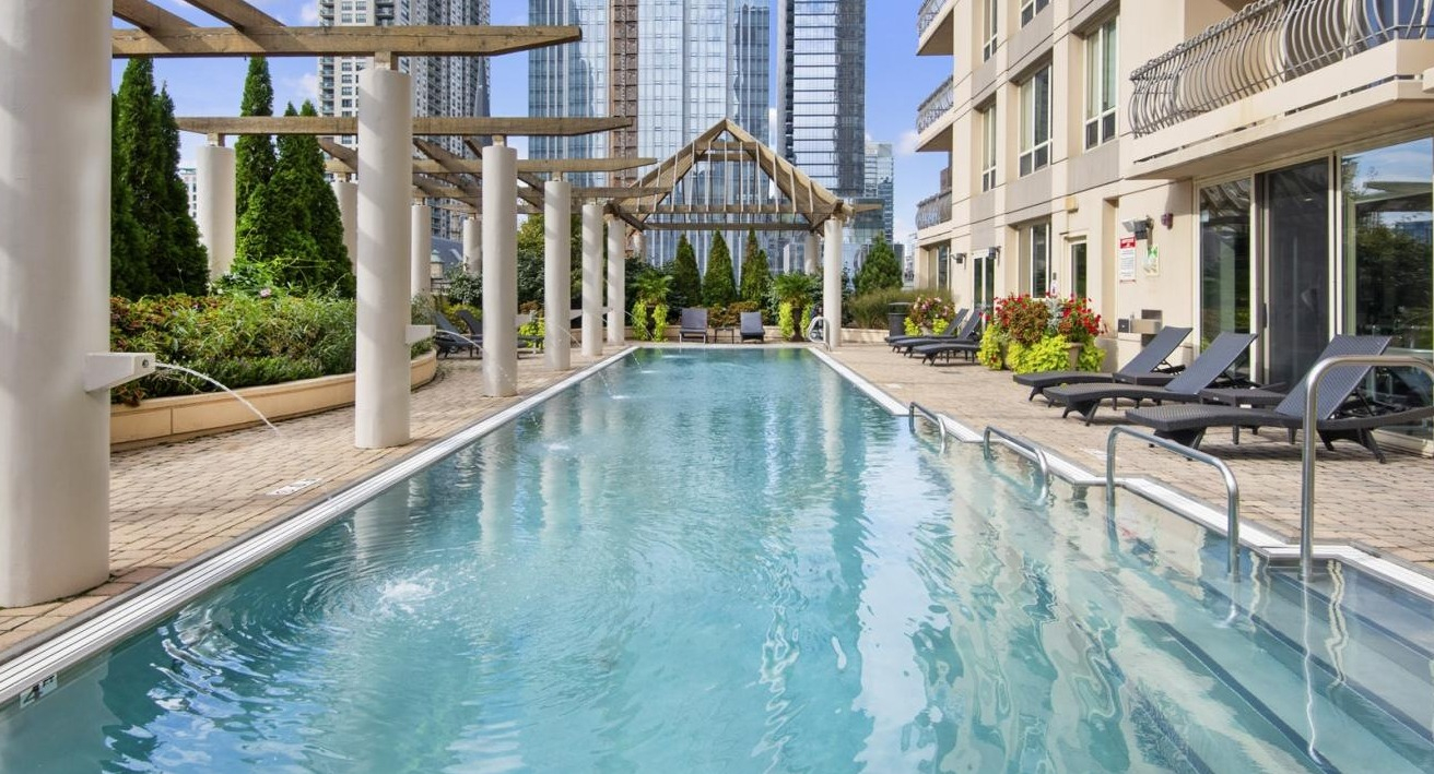 Inviting outdoor lap pool surrounded by elegant pergolas, lush greenery, and comfortable lounge chairs at The Bernardin Apartments in Chicago
