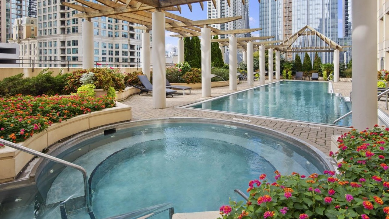 Beautiful outdoor pool and hot tub surrounded by lush landscaping and city views, ideal for relaxation at The Bernardin Apartments in Chicago