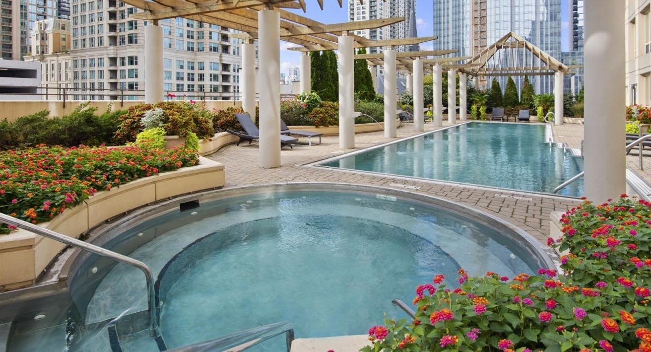 Beautiful outdoor pool and hot tub surrounded by lush landscaping and city views, ideal for relaxation at The Bernardin Apartments in Chicago