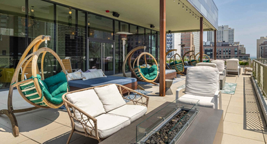 Cozy rooftop patio with wicker lounge furniture, hanging swing chairs, and beautiful views of the Chicago city skyline at The Clark