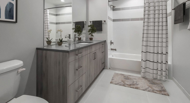 Modern bathroom featuring a spacious vanity with double sinks, contemporary fixtures, and a clean bathtub at The Clark Apartments in Chicago