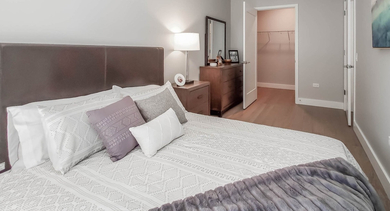 Cozy bedroom with a large bed, stylish decor, and a convenient walk-in closet at The Clark Apartments in Chicago