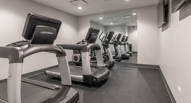 Modern gym with multiple treadmills and cardio machines, perfect for a high-energy workout at The Clark Apartments in Chicago