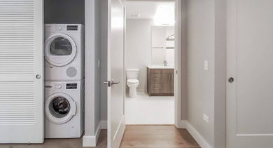 Hallway leading to a hidden in-unit laundry closet and a modern bathroom, showcasing smart apartment design at The Clark Apartments in Chicago