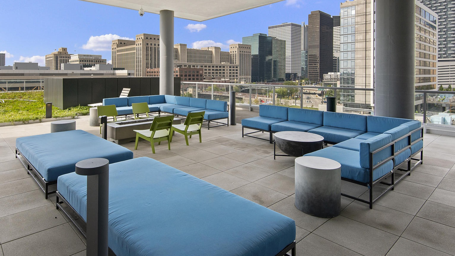 Inviting outdoor lounge area with comfortable blue sofas, a fire pit, and impressive city skyline views at The Cooper apartments in Chicago