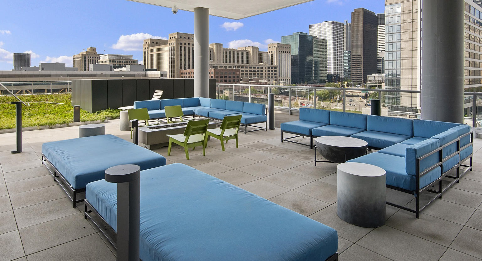Inviting outdoor lounge area with comfortable blue sofas, a fire pit, and impressive city skyline views at The Cooper apartments in Chicago