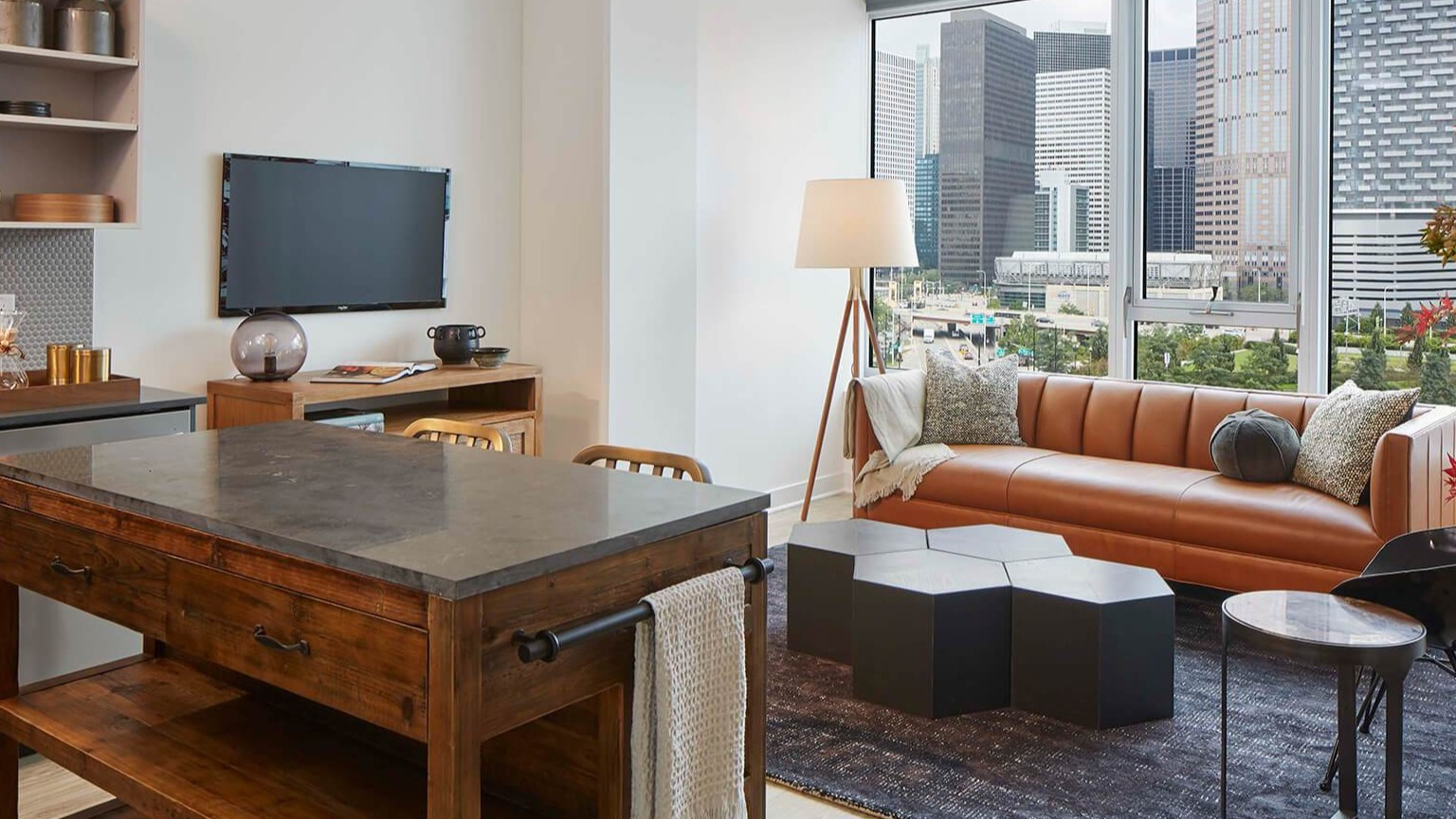 Stylish resident lounge with a comfortable leather sofa, modern lighting, and expansive city views at The Cooper apartments in Chicago