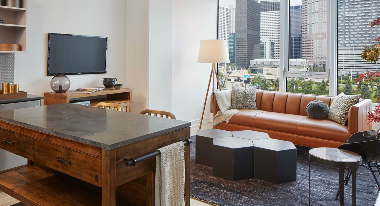 Stylish resident lounge with a comfortable leather sofa, modern lighting, and expansive city views at The Cooper apartments in Chicago