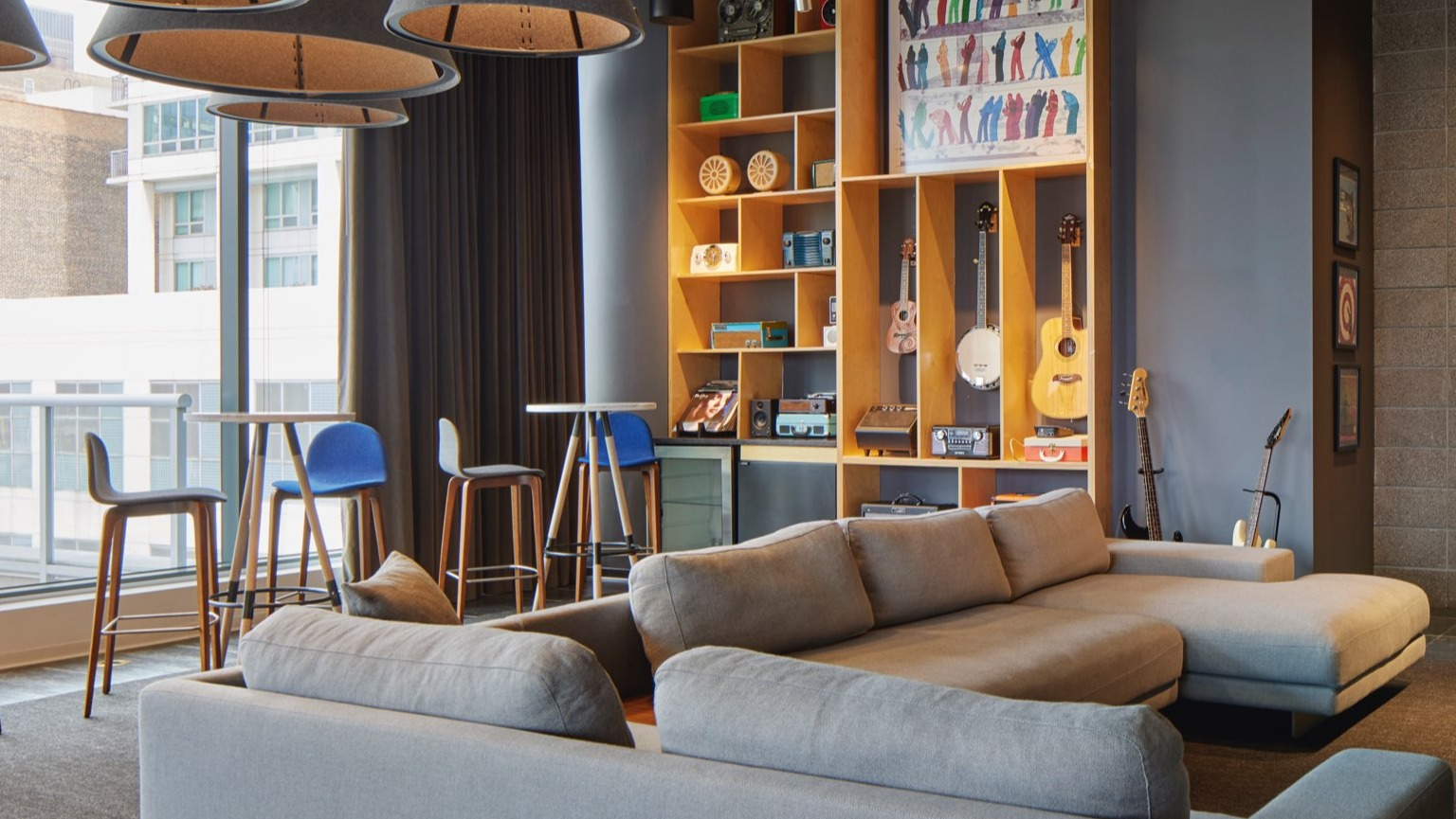 Trendy resident lounge with comfortable sofas, high-top tables, and a stylish shelving unit for entertainment at The Cooper in Chicago
