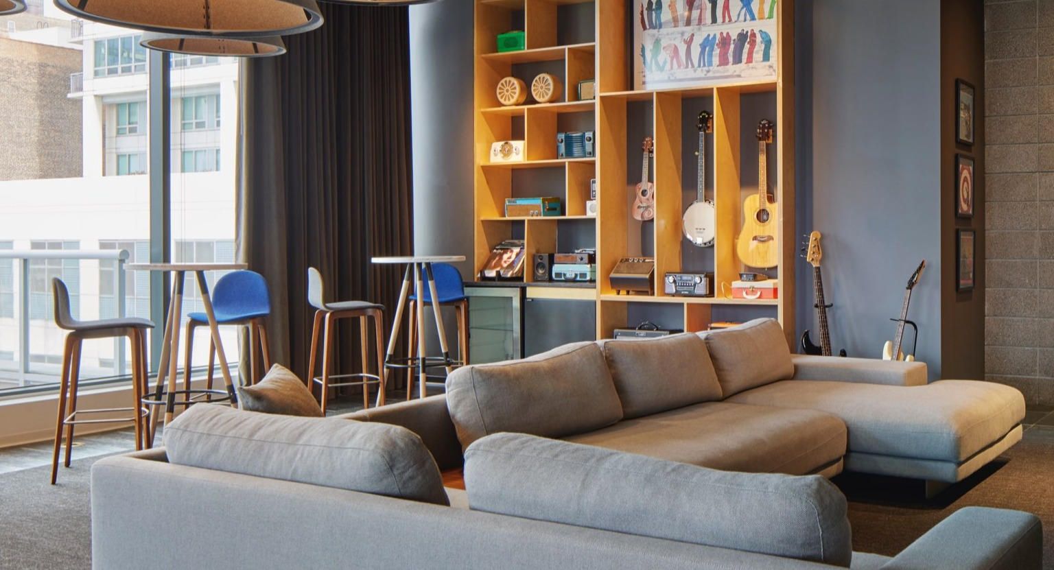 Trendy resident lounge with comfortable sofas, high-top tables, and a stylish shelving unit for entertainment at The Cooper in Chicago