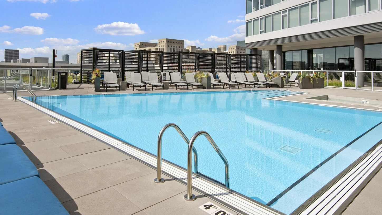 Stunning rooftop pool with lounge chairs and clear blue water, offering a beautiful skyline view at The Cooper apartments in Chicago