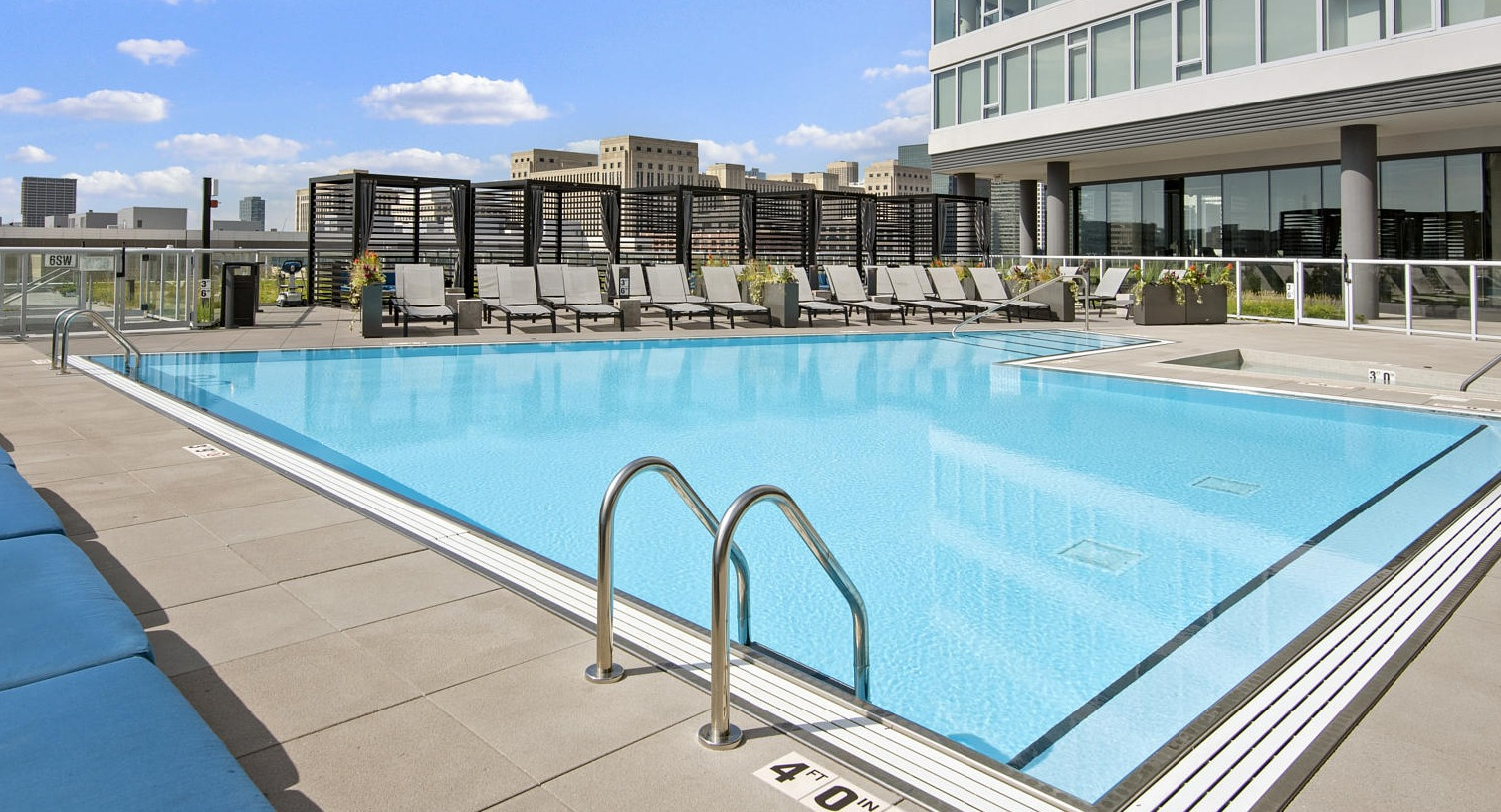 Stunning rooftop pool with lounge chairs and clear blue water, offering a beautiful skyline view at The Cooper apartments in Chicago