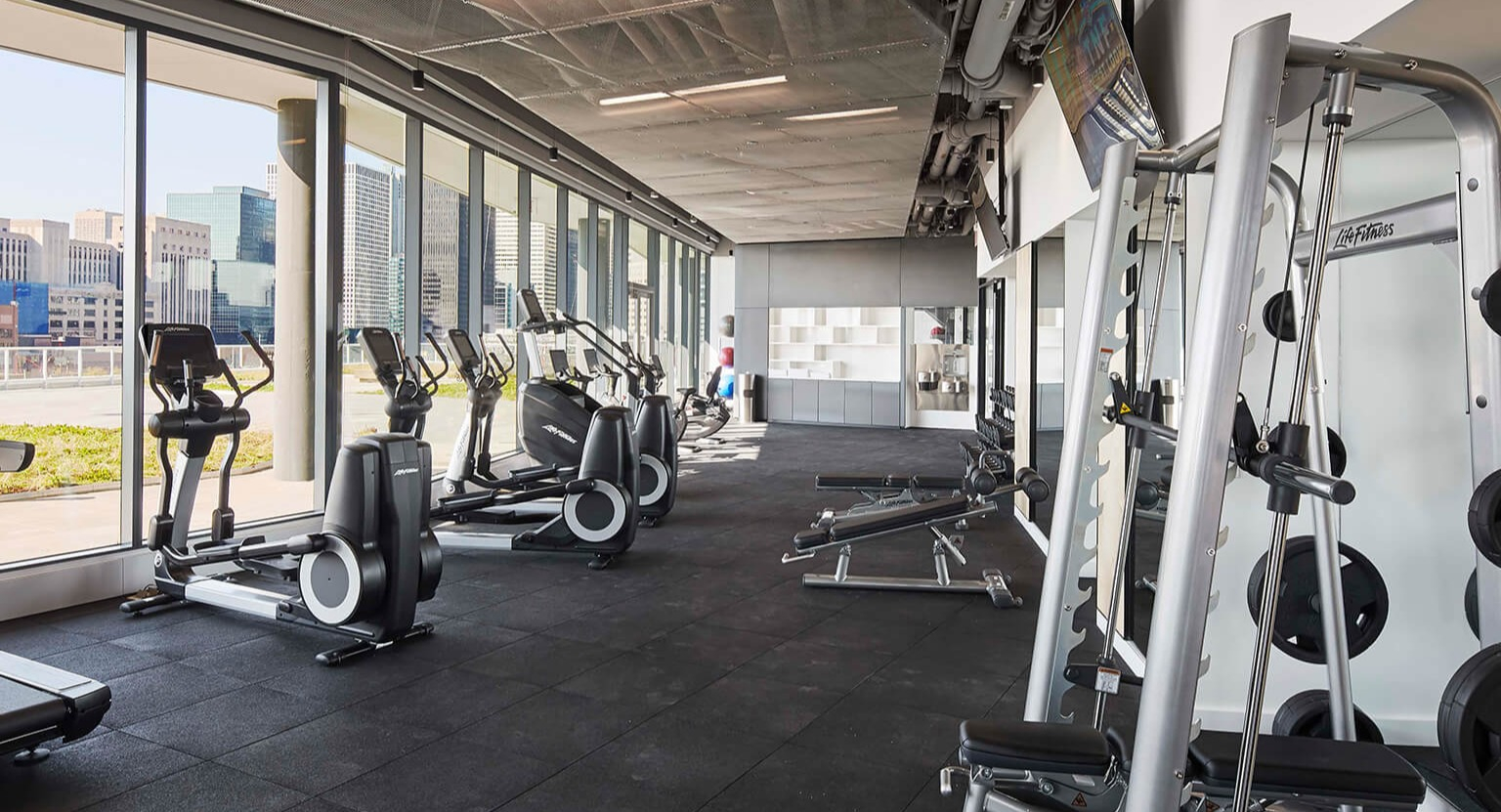 State-of-the-art gym with treadmills, ellipticals, weight machines, and large windows offering city views at The Cooper in Chicago