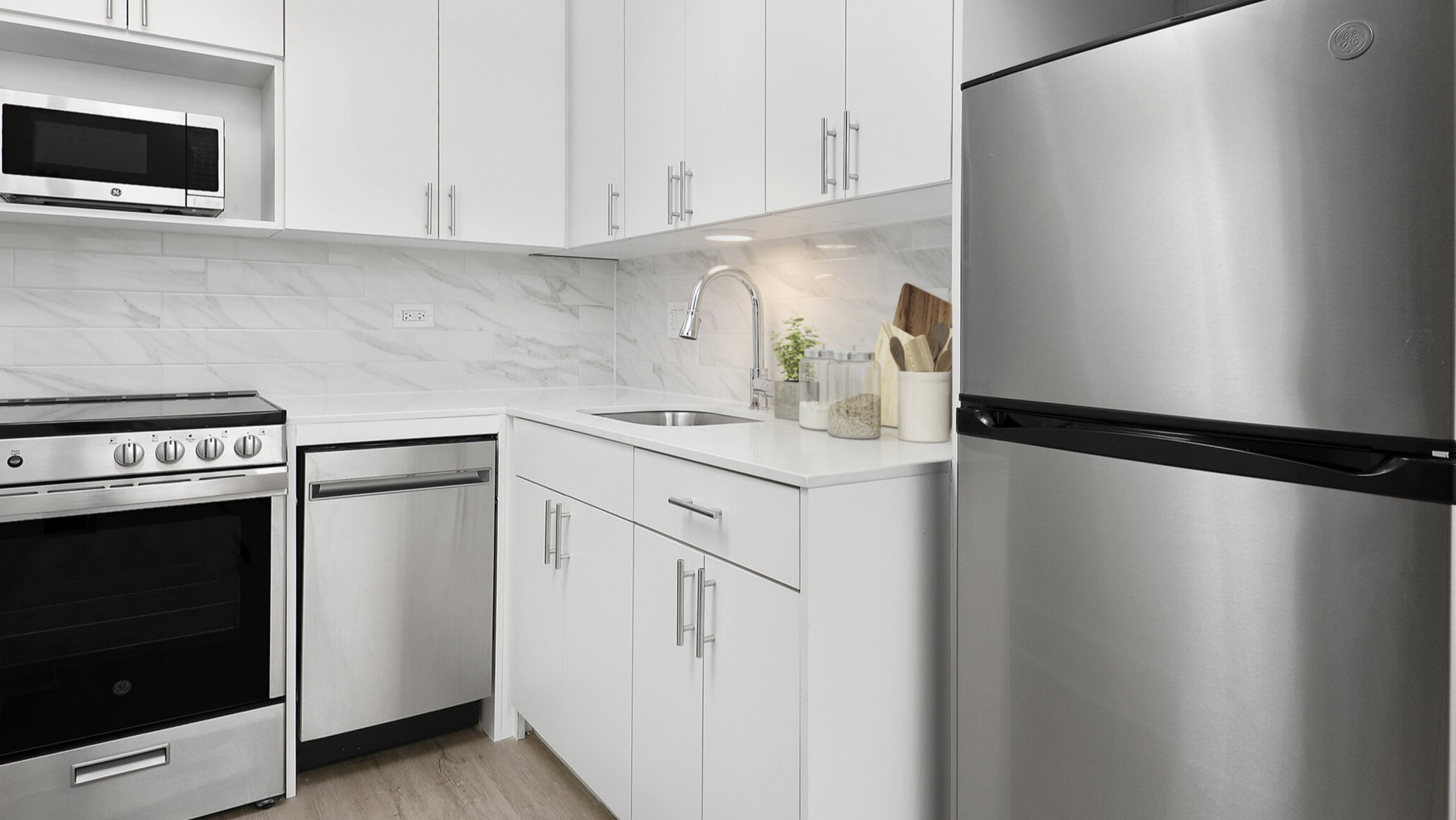 Bright apartment kitchen with white cabinets, stainless steel appliances, and ample counter space at The Deco North Lake Shore in Chicago