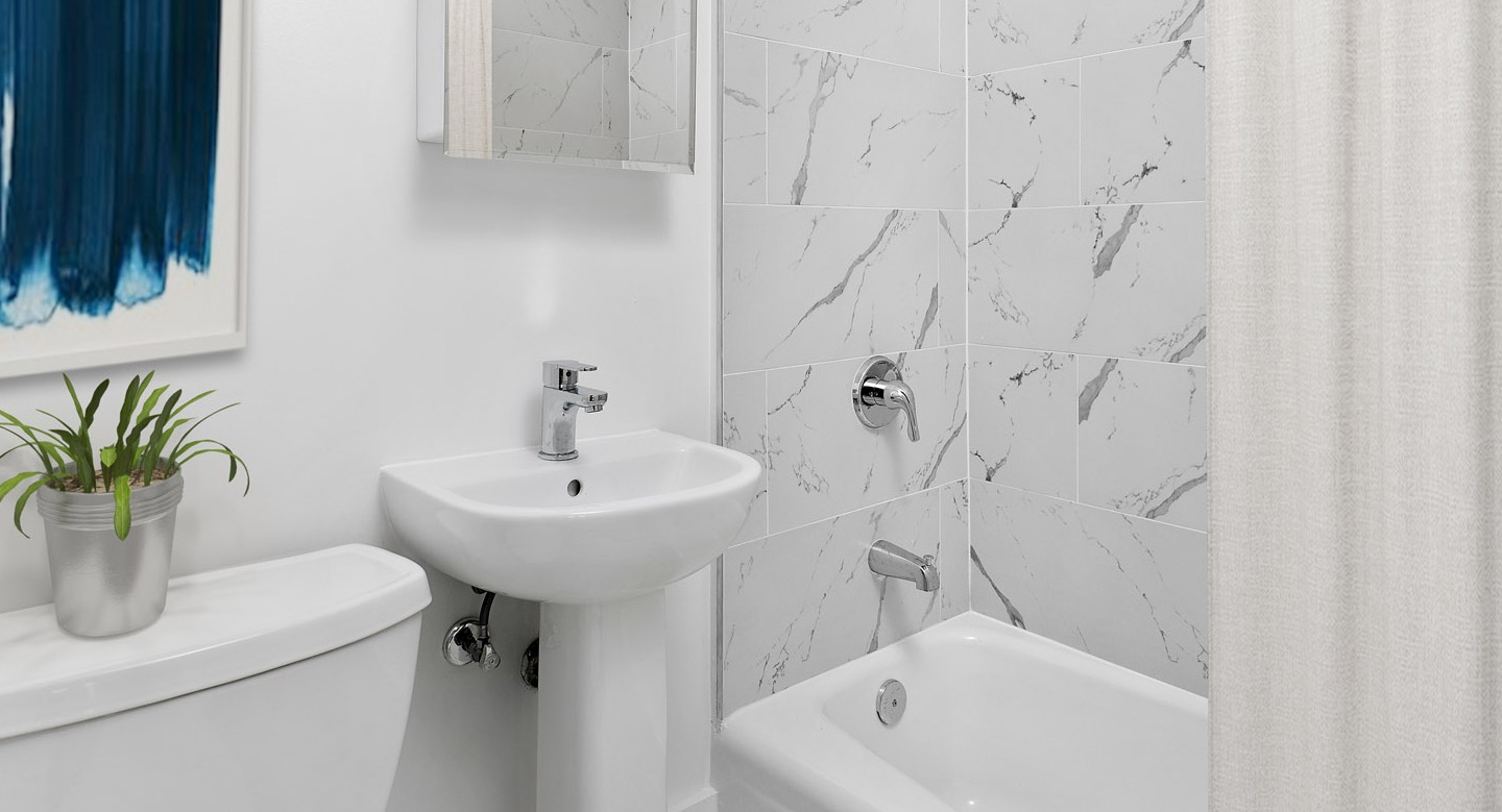 Beautiful bathroom with marble-patterned tiles, a pedestal sink, and a clean white bathtub at The Deco North Lake Shore in Chicago