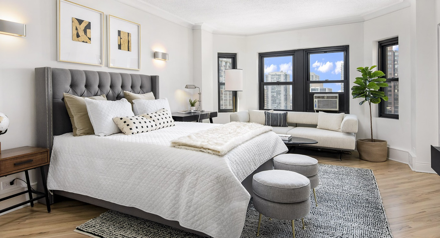 Spacious bedroom with a luxurious bed, decorative accents, and a comfortable lounge area by the windows at The Deco North Lake Shore in Chicago