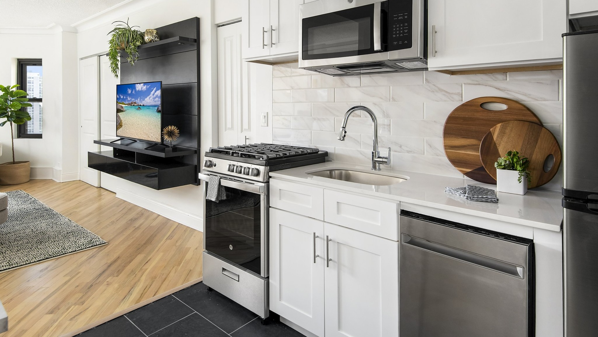 Modern kitchenette with white cabinets, stainless steel appliances, and a seamless flow into the living area at The Deco North Lake Shore in Chicago