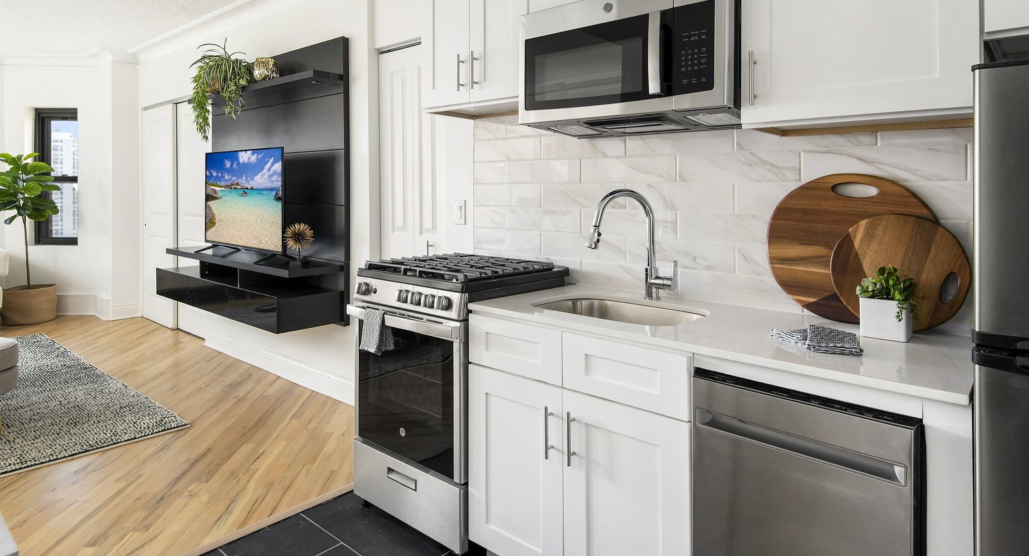 Modern kitchenette with white cabinets, stainless steel appliances, and a seamless flow into the living area at The Deco North Lake Shore in Chicago