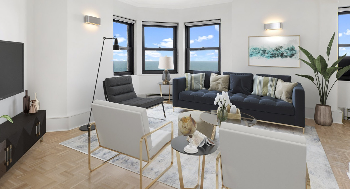Bright modern living room with a navy sofa, white armchairs, sleek media console, and large windows at The Deco North Lake Shore in Chicago