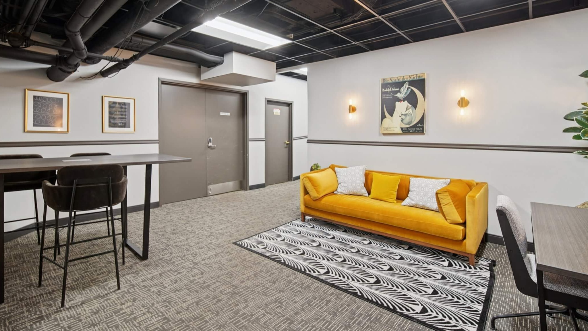 Stylish resident co-working space with a vibrant yellow sofa, high-top tables, and comfortable seating at The Deco North Lake Shore in Chicago