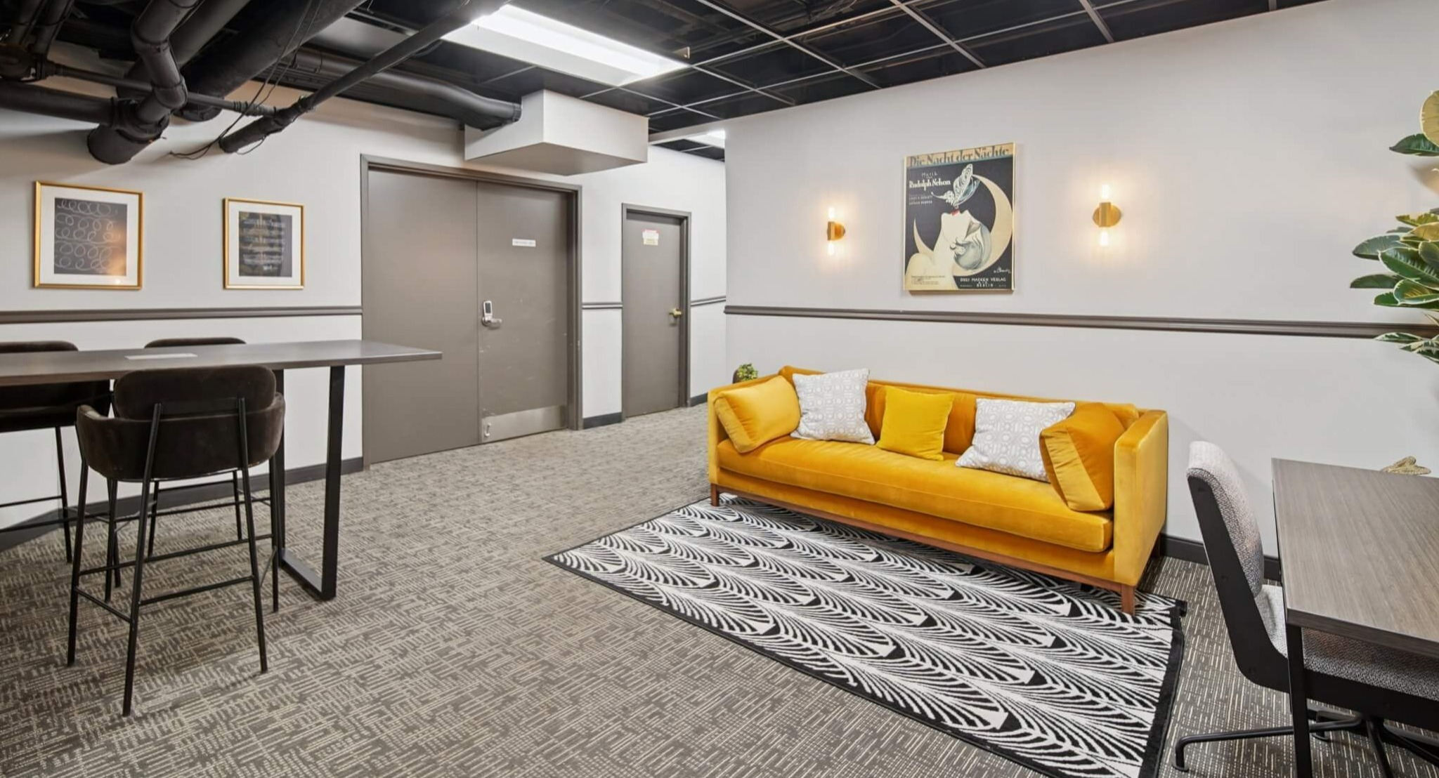 Stylish resident co-working space with a vibrant yellow sofa, high-top tables, and comfortable seating at The Deco North Lake Shore in Chicago