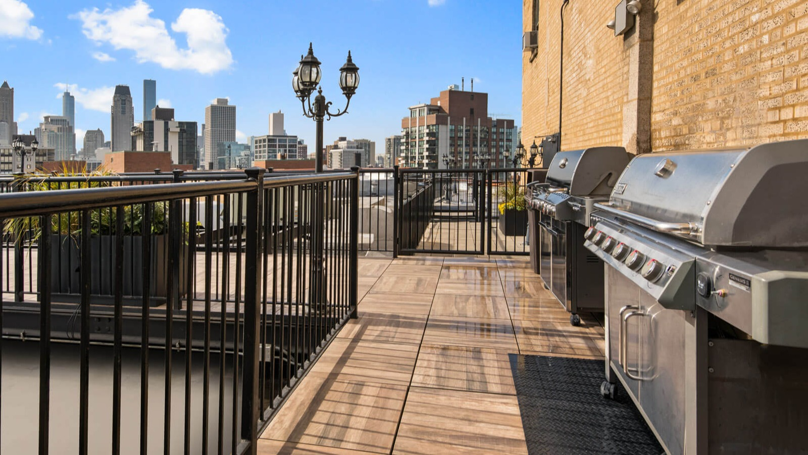 Inviting rooftop grill area with multiple BBQ stations and city skyline views, perfect for outdoor cooking at The Deco North Lake Shore in Chicago