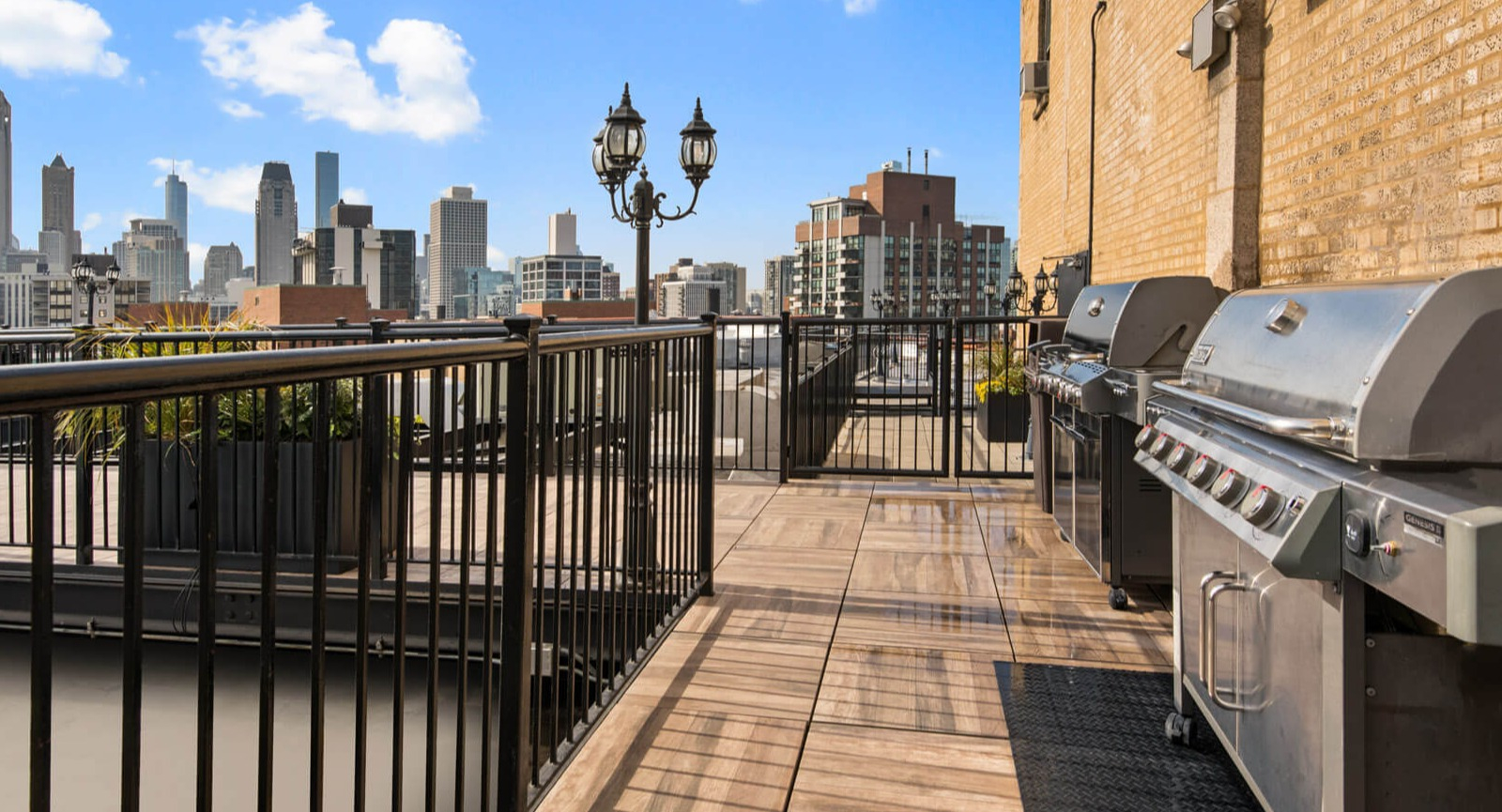 Inviting rooftop grill area with multiple BBQ stations and city skyline views, perfect for outdoor cooking at The Deco North Lake Shore in Chicago